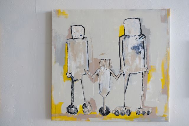 A robot family painted in a stylized blocky and abstract way. The parent robots hold then hand of the child robot whom is situated between the two robots and they are all holding hands.